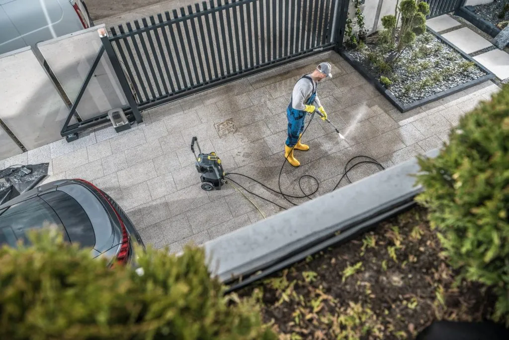 Overhead view of a technician cleaning and sealing a concrete driveway at an Austin home