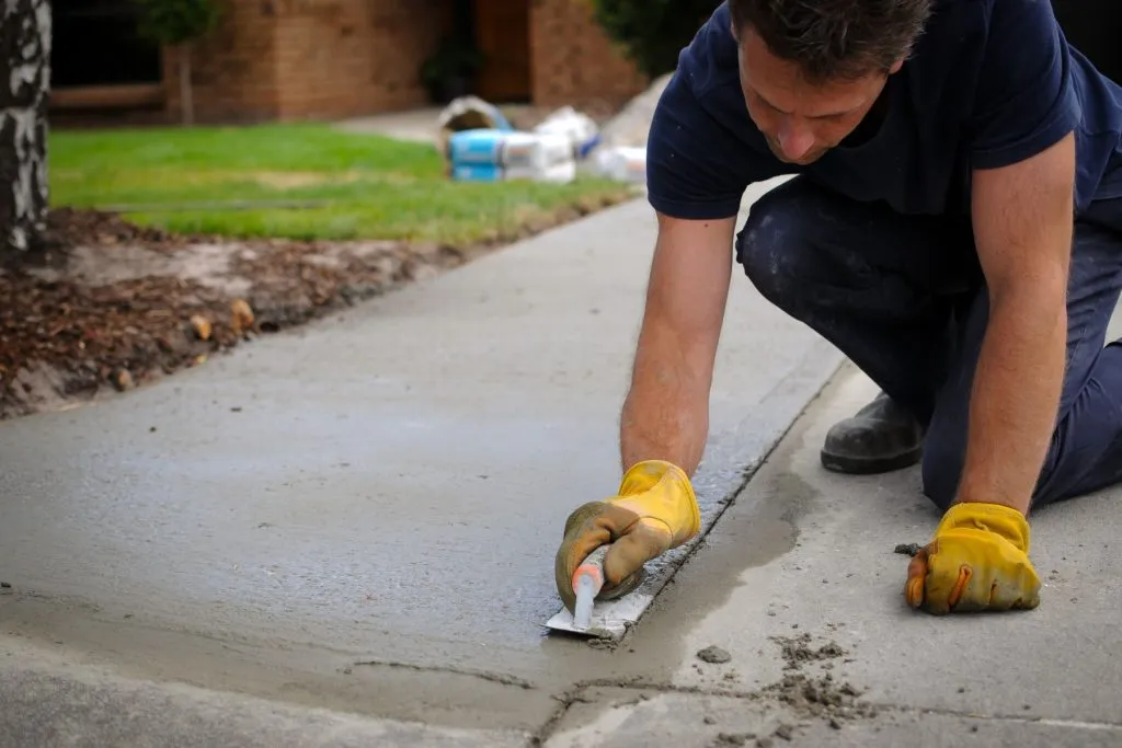 Concrete finisher hand-troweling a driveway edge at an Austin property